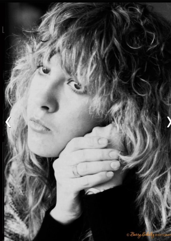 Singer and musician Stevie Nicks of Fleetwood Mac resting her head on her hands staring forward, her hair is cut in a shaggy style and falls over her forehead.